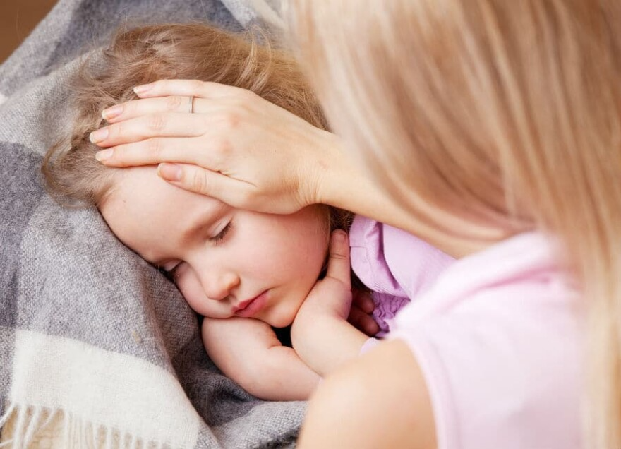 mother putting hand on forehead of sick child